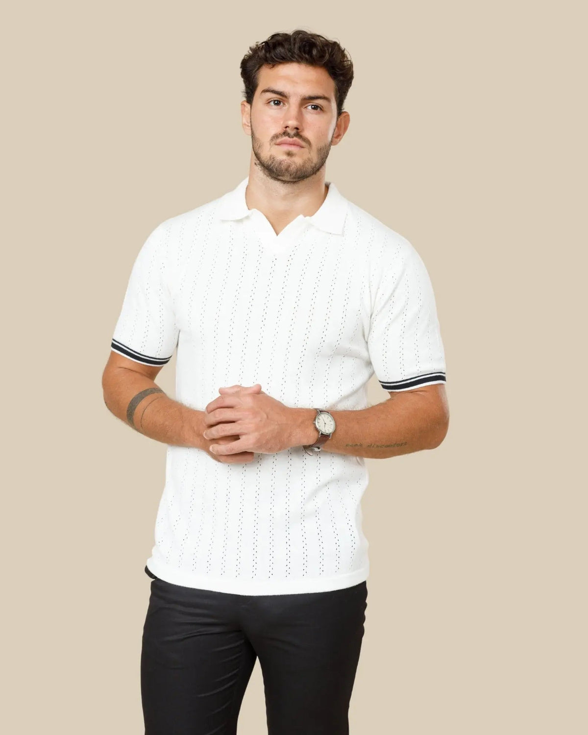 Man wearing a white knitted polo in mercerised cotton, showing the fabric's natural sheen