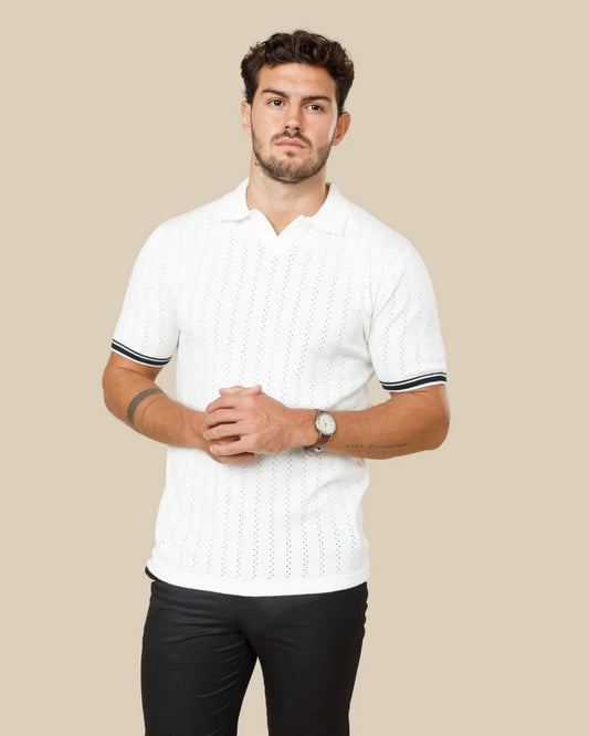 Man wearing a white knitted polo in mercerised cotton, showing the fabric's natural sheen