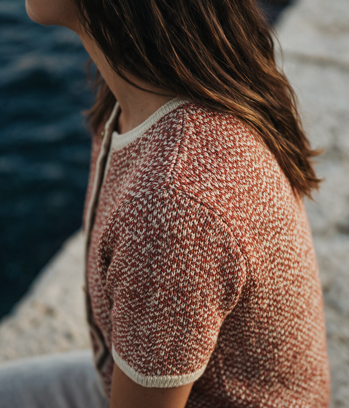 Woman wearing a terracotta and cream contrast-binding knitted cardigan by the coast — Legacy London womenswear