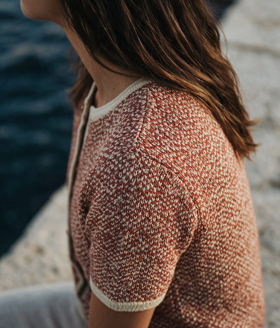 Woman wearing a terracotta and cream contrast-binding knitted cardigan by the coast — Legacy London womenswear